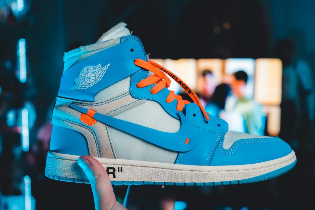 Vibrant University Blue Off-White Nike Jordan 1 sneakers held against a blurred background.